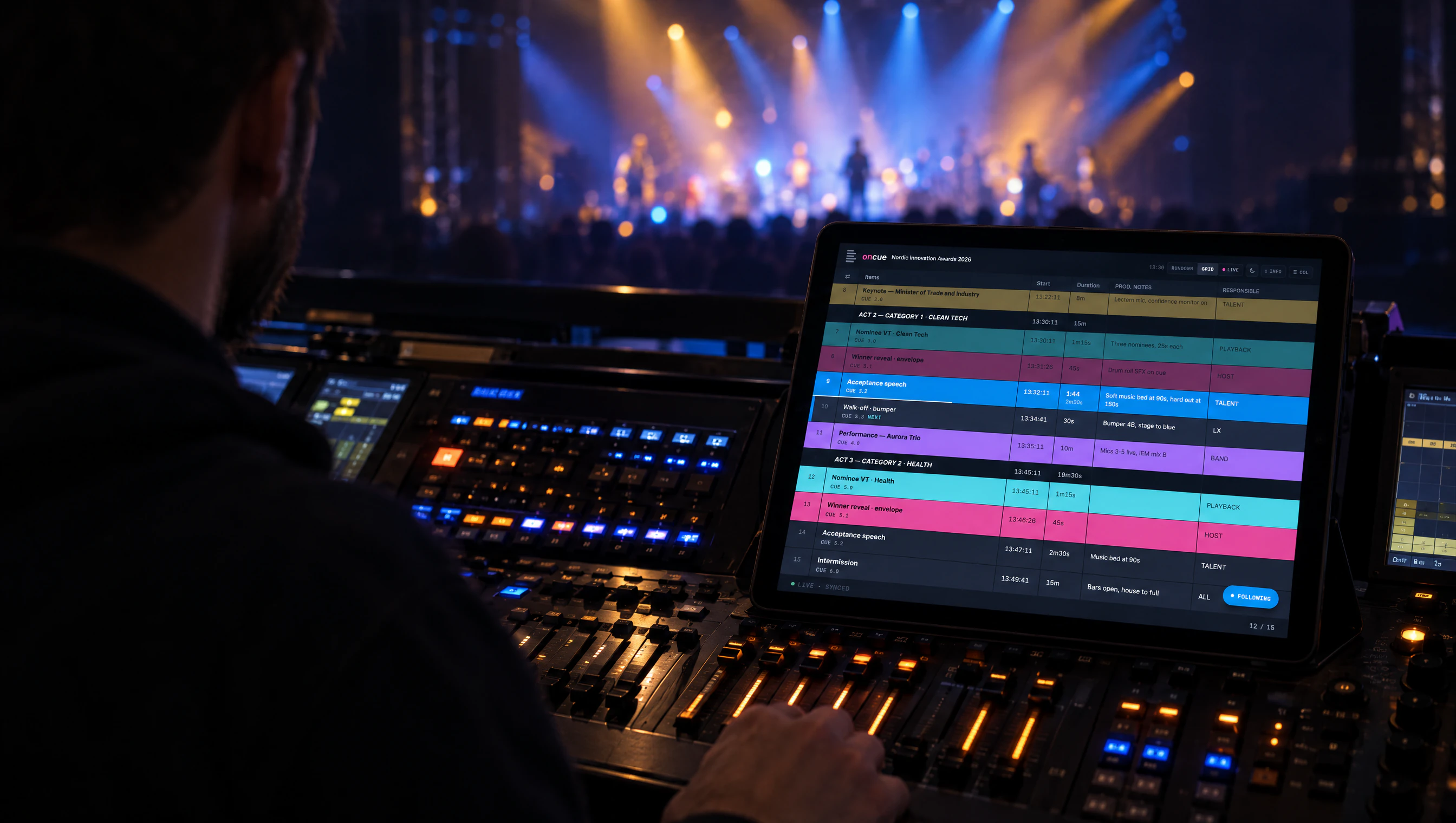 A lighting operator at a console with the OnCue grid viewer on a tablet, stage and crowd lit in blue and amber behind